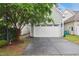 Attached garage with a white door and an adjacent tree at 1212 Sand Pine Dr, Cary, NC 27519