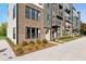 Modern townhome exterior featuring brick facade, black-framed windows, and landscaped front yard at 1242 Coach Station Aly # 101, Raleigh, NC 27601