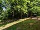 A sloped backyard leading up to a wooded area and outdoor patio at 1307 Montreux Ct, Mebane, NC 27302