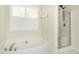 Bright bathroom showcasing a soaking tub, a separate glass shower, and a window with shutter blinds at 1307 Montreux Ct, Mebane, NC 27302
