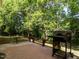 Outdoor patio space with mature trees and a charcoal grill at 1307 Montreux Ct, Mebane, NC 27302