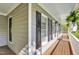 A charming front porch with gray wood-look flooring, gray walls, and white trim and posts at 141 Clay Ridge Way, Holly Springs, NC 27540