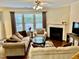 Cozy living room featuring a fireplace, ceiling fan, and large windows with natural light at 1549 Lily Creek Dr, Cary, NC 27518