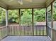 Screened porch with wood floors, black railing and view of green foliage at 1549 Lily Creek Dr, Cary, NC 27518