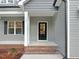 Welcoming front entry with black door, brick steps, gray siding and white trim at 157 Gumtop Dr, Zebulon, NC 27597