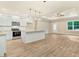 Open kitchen and living area boasts modern appliances, white cabinetry, granite countertops, and wood flooring at 157 Gumtop Dr, Zebulon, NC 27597