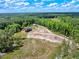 Picturesque aerial view of a log home, barn, and cleared acreage surrounded by dense woodlands on a sprawling property at 2092 Winwood Farm Rd, Creedmoor, NC 27522