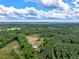 An aerial view shows the house and barn on a property surrounded by beautiful green trees at 2092 Winwood Farm Rd, Creedmoor, NC 27522
