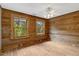 Bright bedroom featuring paneled wood walls, two large windows, and modern ceiling fan at 2092 Winwood Farm Rd, Creedmoor, NC 27522