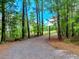 Picturesque gravel driveway lined with lush trees, offering a secluded and inviting entrance to the estate at 2092 Winwood Farm Rd, Creedmoor, NC 27522