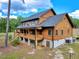 Two-story log cabin-style home featuring a raised porch with basement and set against a backdrop of trees and sky at 2092 Winwood Farm Rd, Creedmoor, NC 27522