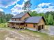 Aerial view of a two-story log home with an attached garage, and long driveway surrounded by lush greenery at 2092 Winwood Farm Rd, Creedmoor, NC 27522