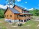 Two-story log cabin-style home featuring a raised porch with basement and set against a backdrop of trees and sky at 2092 Winwood Farm Rd, Creedmoor, NC 27522