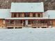 Charming log home with a spacious front porch covered in a blanket of fresh, white snow at 2092 Winwood Farm Rd, Creedmoor, NC 27522