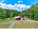 Aerial view of a red metal outbuilding, with dual bay access, set on a large, verdant, tree-lined lot at 2092 Winwood Farm Rd, Creedmoor, NC 27522