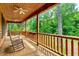 This porch features an outdoor rocking chair, wood railing, and a ceiling fan at 2092 Winwood Farm Rd, Creedmoor, NC 27522