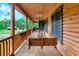 Inviting log cabin porch featuring wooden railing and porch swing, perfect for relaxing outdoors at 2092 Winwood Farm Rd, Creedmoor, NC 27522