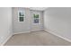 This bedroom has neutral carpet, light-colored walls, and two windows at 2100 Curry Meadow Way, Durham, NC 27703