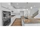 Bright kitchen features white cabinetry, stainless appliances, granite countertops, and island with stainless sink at 2100 Curry Meadow Way, Durham, NC 27703