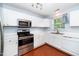 Well-lit kitchen with white cabinets, stainless steel appliances, and hardwood floors at 216 Climbing Ivy Ct, Cary, NC 27511