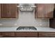 Detailed view of the stainless steel range hood, gas cooktop, and sleek tile backsplash at 2501 Macedonia Pine Dr, Raleigh, NC 27616