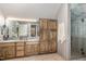 Bathroom featuring double sinks, custom wood cabinetry, and step-in shower at 27425 Walker, Chapel Hill, NC 27517