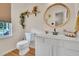 Bright bathroom featuring a vanity with a round mirror, toilet, stylish shelf decor, and wood flooring at 31 Bucking Saddle Way, Willow Springs, NC 27592