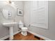 A half bathroom with a pedestal sink, toilet, and window with plantation shutters at 312 Bridgegate Dr, Cary, NC 27519