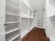 A large walk-in closet with custom shelving, rods, and dark wood floors for organized storage at 312 Bridgegate Dr, Cary, NC 27519