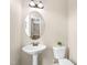 Powder room with a pedestal sink, toilet, and oval mirror at 317 Chamberlain Dr, Clayton, NC 27527