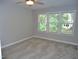 Neutral bedroom with three sunny windows, plush carpeting, and a ceiling fan at 3300 Neuse Crossing Dr, Raleigh, NC 27616