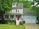 Charming two-story home with a red front door, covered porch, lush landscaping, and an attached two-car garage at 3300 Neuse Crossing Dr, Raleigh, NC 27616
