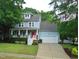 Charming two-story home with a red front door, covered porch, lush landscaping, and an attached two-car garage at 3300 Neuse Crossing Dr, Raleigh, NC 27616