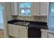 Modern kitchen features stainless steel sink, sleek black countertops, and white cabinetry at 3300 Neuse Crossing Dr, Raleigh, NC 27616