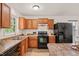 Bright kitchen featuring wood cabinetry and sleek black appliances at 34 Johnston St, Pittsboro, NC 27312