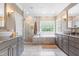 Elegant bathroom with double sinks, granite countertops, tiled shower, and soaking tub, offering a spa-like experience at 3821 Falls River Ave, Raleigh, NC 27614
