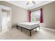 Simple bedroom features a bed frame, a window with dark pink curtains, and neutral walls at 3821 Falls River Ave, Raleigh, NC 27614