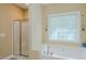 Bright bathroom featuring a soaking tub with a glass block window and a separate glass door shower at 4667 Freedom Dr, Burlington, NC 27215