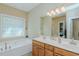 Bathroom with double sinks and vanity, along with a soaking tub below a translucent window at 4667 Freedom Dr, Burlington, NC 27215
