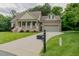 View of driveway leading to brick home with manicured front lawn, shrubs and mailbox at 4667 Freedom Dr, Burlington, NC 27215