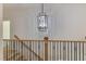 Hallway with view of modern chandelier, wood railing, and staircase at 4921 Sweetbriar Dr, Raleigh, NC 27609