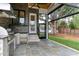 Outdoor kitchen with stainless steel grill, fridge, bar seating, stone wall, and screened porch at 4921 Sweetbriar Dr, Raleigh, NC 27609
