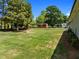 Backyard with lush lawn, mature trees, a shed, and a firepit, creating a serene outdoor retreat at 5208 Melbourne Rd, Raleigh, NC 27606