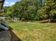 Expansive backyard featuring a lush lawn, mature trees, a firepit and a shed, perfect for outdoor activities at 5208 Melbourne Rd, Raleigh, NC 27606