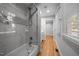 Bathroom with tub, glass shower, marble tile, and window letting in natural light at 5208 Melbourne Rd, Raleigh, NC 27606