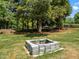 Built-in firepit featuring a stone surround, set amidst a spacious lawn and mature trees, ideal for outdoor relaxation at 5208 Melbourne Rd, Raleigh, NC 27606