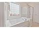 Bright bathroom featuring a soaking tub, glass enclosed shower, and a window with privacy glass at 524 Clarenbridge Dr, Cary, NC 27519