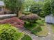 Landscaped backyard with brick home, stone walkway, and mature trees at 5529 Shadowbrook Dr, Raleigh, NC 27612