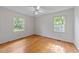 Bright bedroom featuring hardwood floors, ceiling fan, and natural light from two windows at 5529 Shadowbrook Dr, Raleigh, NC 27612