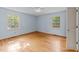 Bedroom with two windows, light blue walls, ceiling fan, and wood floors at 5529 Shadowbrook Dr, Raleigh, NC 27612